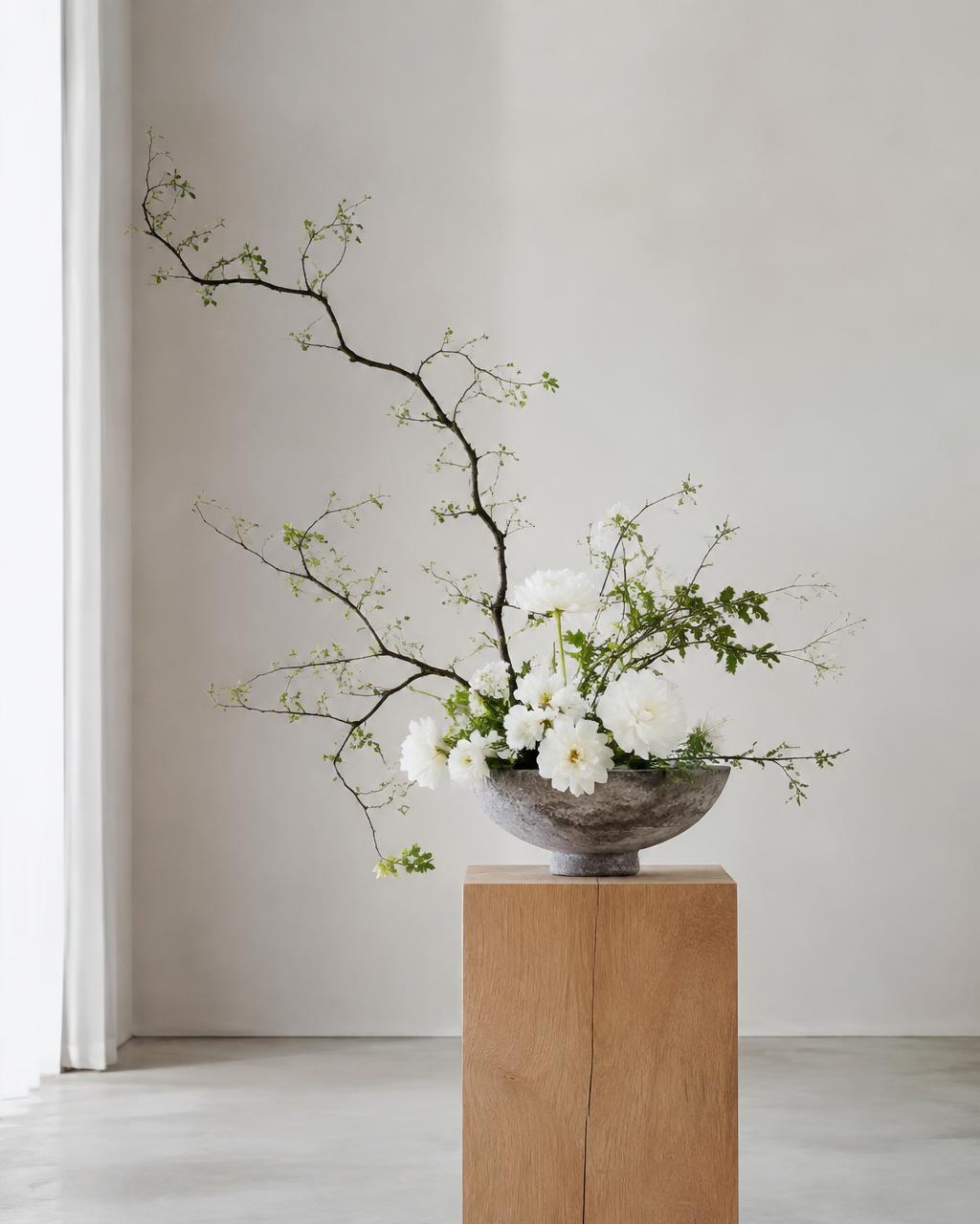 Ikebana s větvemi a bílými květy v kamenné misce